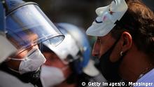 BERLIN, GERMANY - AUGUST 29: A man wearing a masquerade mask on his head speaks to a police officer as coronavirus skeptics and right-wing extremists march in protest against coronavirus-related restrictions and government policy on August 29, 2020 in Berlin, Germany. City authorities had banned the planned protest, citing the flouting of social distancing by participants in a similar march that drew at least 17,000 people a few weeks ago, but a court overturned the ban. (Photo by Omer Messinger/Getty Images)
