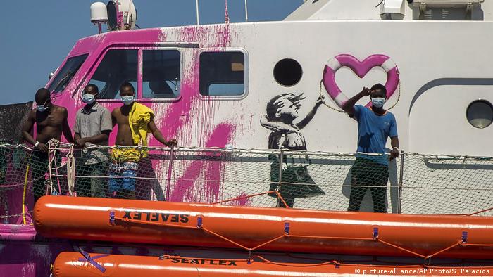 Banksy-Rettungsboot Louise Michelmit Migranten, auf der Seite sieht man ein Mädchen mit Rettungsring aufgemalt  