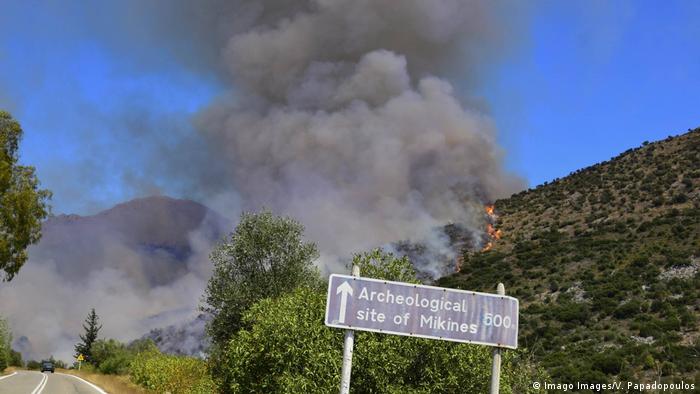 Дым, огонь и указатель по дороге к археологическому памятнику Микен