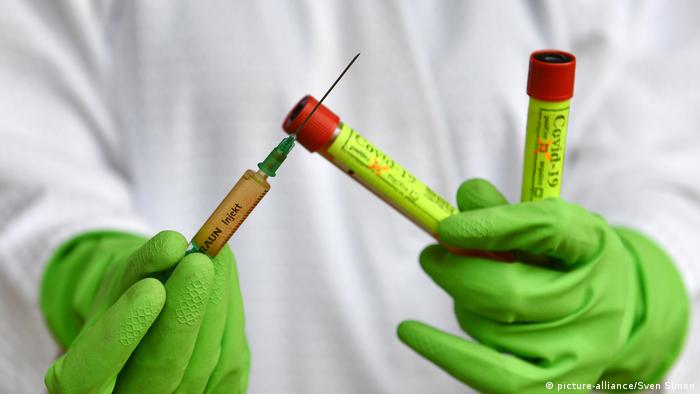 Руки в перчатках держат шприц с вакциной-кандидатом против коронавируса