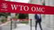An unknown delegate walks behind a red WTO sign An unknown delegate walks behind a red WTO sign