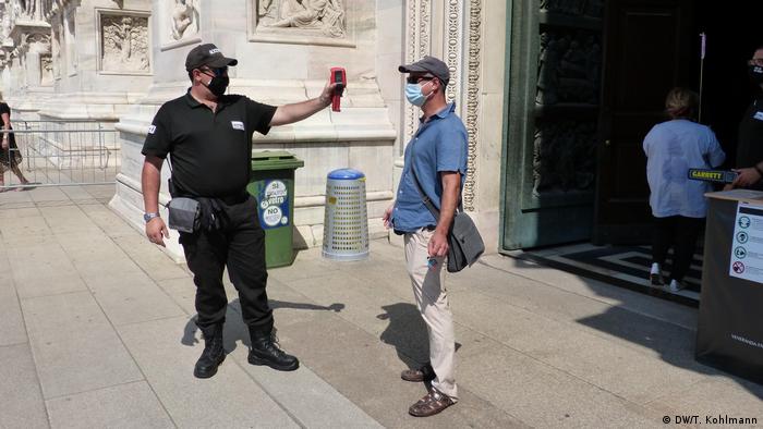 Security worker takes visitors' temperatures at Milan Duomo (DW/T. Kohlmann)