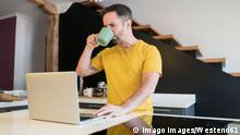 Man drinking coffee while using laptop on kitchen island at home model released Symbolfoto property released MTBF00470 