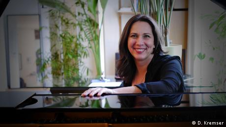Pianistin Susanne Kessel sitzt an ihrem Flügel und lächelt in die Kamera.