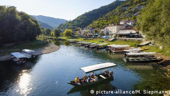 Люди в лодке плывут по реке в национальном парке около черногорского города Цетине