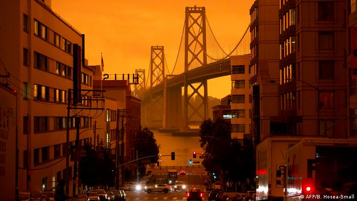 The San Francisco Bay Bridge is seen along Harrison Street under an orange smoke-filled sky in San Francisco