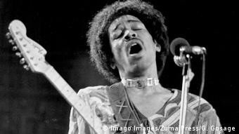 Jimi Hendrix auf der Bühne, spielt mit ausladender Bewegung E-Gitarre