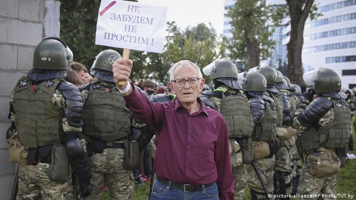Пожилой участник протестов держит плакат: Не забудем. Не простим. 