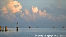 13.09.2020, A man fishes standing atop the remains of the stilt of an old dock, in the municipality of Tela, Atlantida department on the Caribbean Sea, 250 km north of Tegucigalpa, on September 13, 2020, during the Covid-19 coronavirus pandemic. (Photo by ORLANDO SIERRA / AFP) (Photo by ORLANDO SIERRA/AFP via Getty Images)