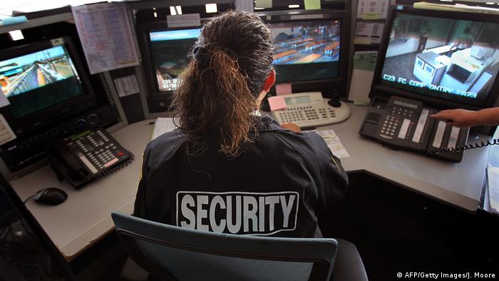 A guard monitors surveillance cameras at an ICE detention facility