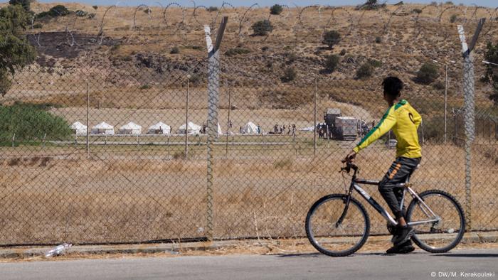 A refugee man on a bicycle stops to look at the newly built temporary camp that was set up on Lesbos after Moria's destruction. (DW/M. Karakoulaki)