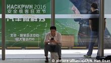 An attendee uses his smartphone near an advertisement for a computer hacker festival during the 4th China Internet Security Conference (ISC) in Beijing, Tuesday, Aug. 16, 2016. Despite China's tight controls on the flow of information on the internet, online fraud and identity theft are posing major challenges to authorities as e-commerce and other online services boom. (AP Photo/Ng Han Guan) |