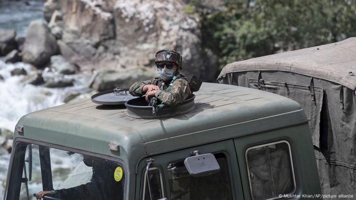 An Indian army soldier keeps guard on top of his vehicle