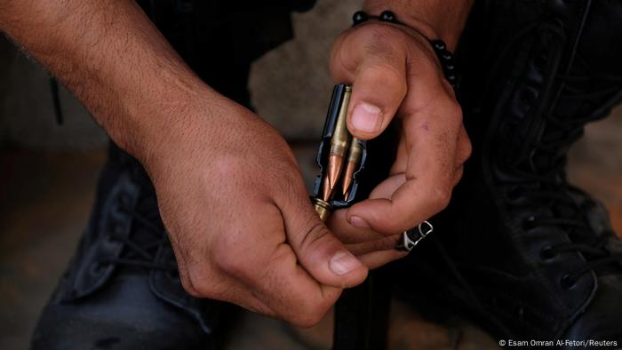Foto simbólica de unas manos que cargan balas de un fusil.
