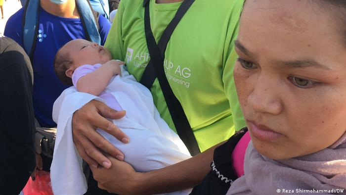 Afghan migrants hold a baby in the Kara-Tepe camp on the island of Lesbos, Greece