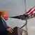 Дональд Трамп на фоне как бы вылетающего из его рта и развевающегося на ветру флага США