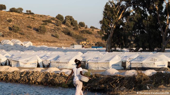 A young woman returns to the camp after washing he clothes in the sea.