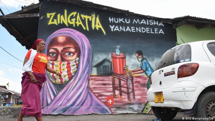A woman walks past by a graffiti in Dar es Salaam