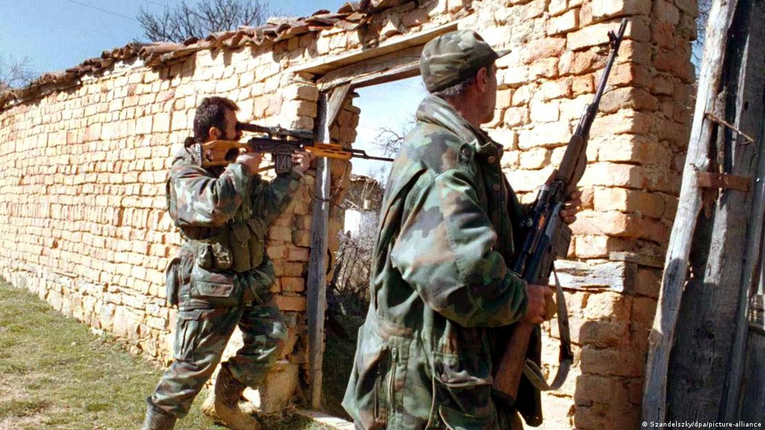 Kosovo-Konflikt | Bewaffnete UCK-Kämpfer gehen hinter einem Gebäude in Deckung Kosovo-Konflikt | Bewaffnete UCK-Kämpfer gehen hinter einem Gebäude in Deckung