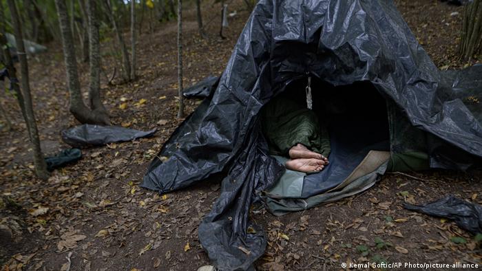 A migrant rests in a tent improvised from plastic sheets at a makeshift camp in a forest outside Velika Kladusa, Bosnia