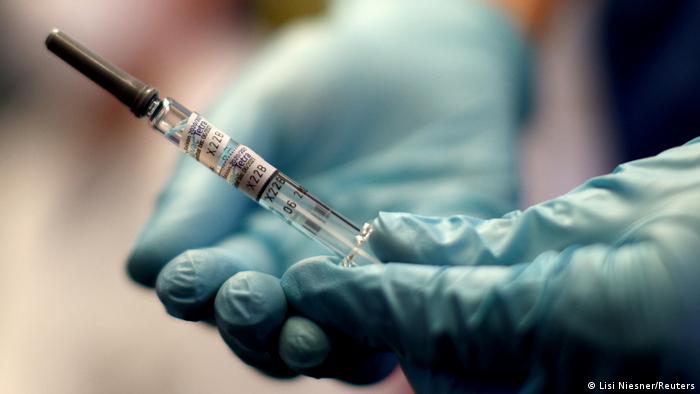 Mãos com luvas azuis seguram seringa com vacina