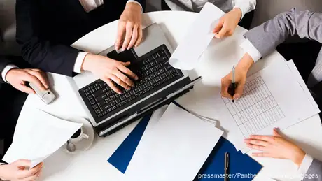 People working in a group with a laptop and paper documents