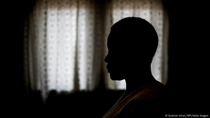 A woman sitting in the darkness of her house 학대: 아프리카