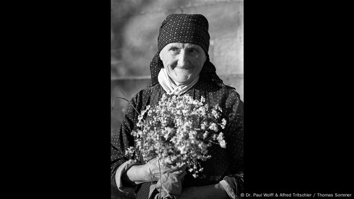Alte Bauersfrau mit lächelt mit einem Blütenstrauß in der Hand (Dr. Paul Wolff & Alfred Tritschler / Thomas Sommer)