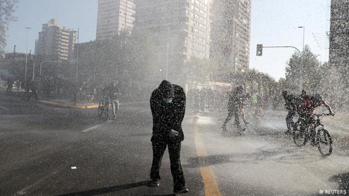 Foto de manifestantes bajo chorros de agua en Santiago de Chile