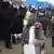 Пожилая женщина в защитной маске и с букетом в руках перед цепью омоновцев на акции протеста в Минске