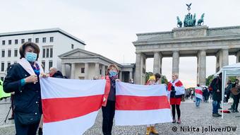Акция солидарности в Берлине с протестующими в Беларуси - люди у Бранденбургских ворот с бело-красно-белыми флагами