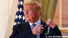 U.S. President Donald Trump pulls off his protective face mask as he poses atop the Truman Balcony of the White House after returning from being hospitalized at Walter Reed Medical Center for coronavirus disease (COVID-19) treatment, in Washington, U.S. October 5, 2020. REUTERS/Erin Scott