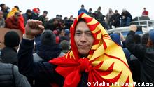 A demonstrator wearing the national flag gestures during a protest against the results of a parliamentary election in Bishkek, Kyrgyzstan, October 6, 2020. REUTERS/Vladimir Pirogov