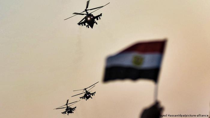 Three helicopters fly past an Egyptian flag