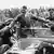 Hitler is mobbed by supporters while standing in a car during a rally