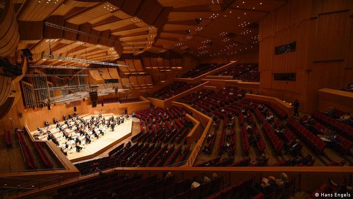 Weitwinkel Bild vom Konzertsaal mit dem Orchester auf der erleuchteten Bühne.