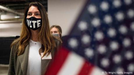 Una mujer estadounidense con mascarilla donde se lee: Vote.