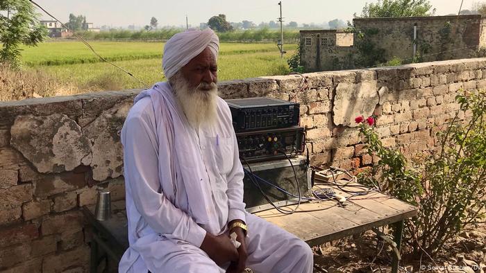 A man sits alone next to a wall