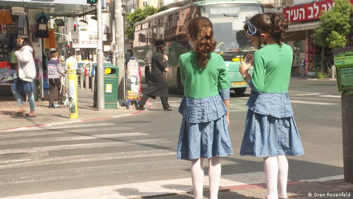 Two young girls standing at pedestrian crossing in Bnei Brak, Israel