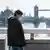 A man walks close to Tower Bridge wearing a mask