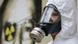 Ein Mann in einem weißen Schutzanzug mit einer Atemmaske steht vor dem schwarz-gelben Symbol für radioaktive Strahlung (Foto: AP) Ein Mann in einem weißen Schutzanzug mit einer Atemmaske steht vor dem schwarz-gelben Symbol für radioaktive Strahlung (Foto: AP)