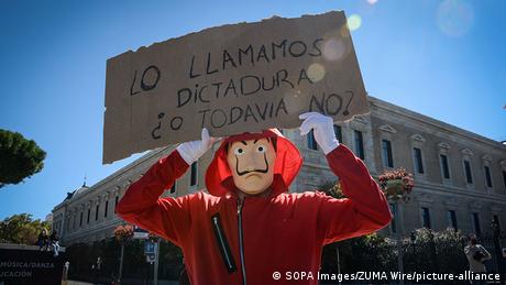A person in a mask holding up a sign (SOPA Images/ZUMA Wire/picture-alliance)