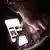 A teen looks at a smartphone screen in the dark
