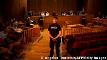 A police officer stands ready as Judge Maria Lepenioti (Back-C) announces the verdict in the trial of suspected members of neo-Nazi party Golden Dawn accused of the September 2013 murder of the anti-fascist rapper, in Athens on October 14, 2020. - A Greek court handed a 13-year prison sentence to the leader of neo-Nazi group Golden Dawn for running a criminal organisation disguised as a political party. As well as Nikos Michaloliakos, the party's founder -- who received an additional one year for illegal possession of a weapon -- the court also sentenced five former members of his inner circle to prison terms on the criminal organisation charge. (Photo by ANGELOS TZORTZINIS / AFP) (Photo by ANGELOS TZORTZINIS/AFP via Getty Images)