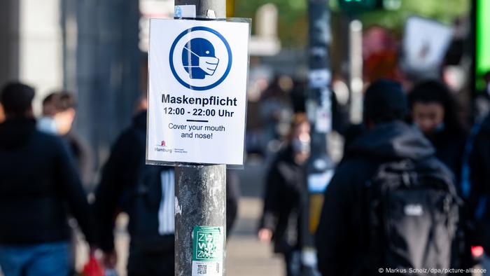 Cartaz numa rua de Hamburgo avisa aos pedestres do uso obrigatório de máscara entre 12 e 22 horas. Cartaz numa rua de Hamburgo avisa aos pedestres do uso obrigatório de máscara entre 12 e 22 horas.