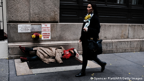 A woman walks by a homeless man along a Manhattan street.
