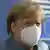 Angela Merkel wearing a mask in front of an EU logo