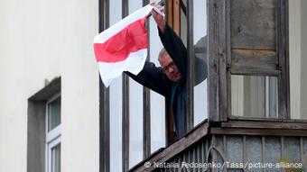 Житель Минска держит бело-красно- белый флаг в знак солидарности с протестующими против Лукашенко Житель Минска держит бело-красно- белый флаг в знак солидарности с протестующими против Лукашенко