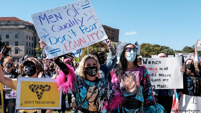 Frauen demonstrieren mit Protestschildern und Masken