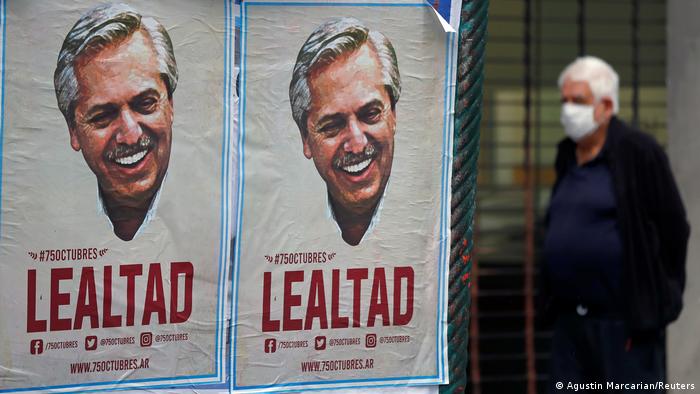 Foto de un hombre que camina cerca de un afiche con la cara de Alberto Fernández que dice lealtad